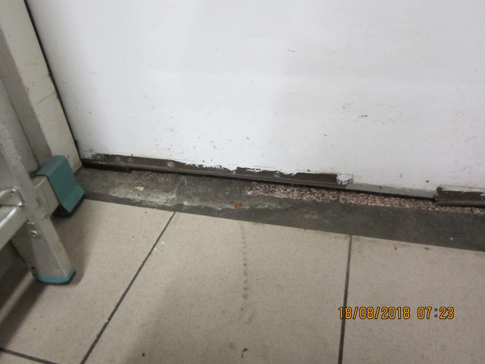 Poškodená podlaha pod vstupnými dverami na príjem tovaru.