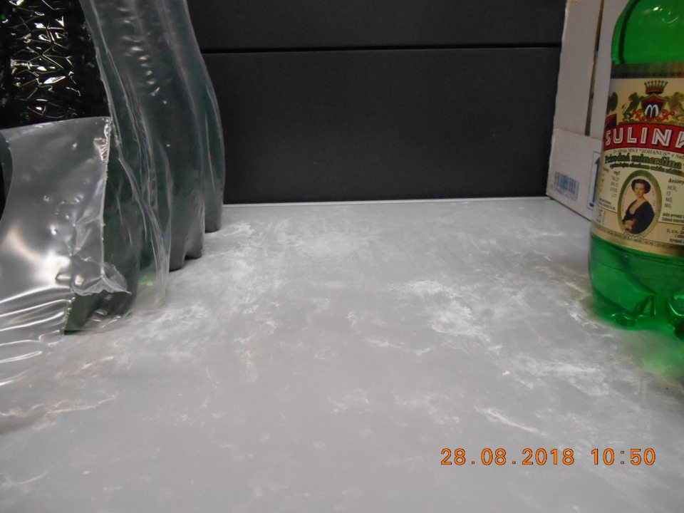 Znečistený regál pod minerálnymi vodami na predajnej ploche.