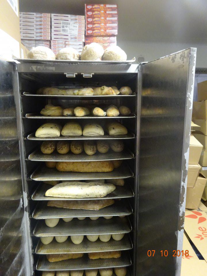 Hlbokozmrazené pekárske polotovary uložené na táckach v kovovej skrini, pričom jedna tácka bola uložená na kovovej skrini bez akejkoľvek ochrany pred vonkajšími vplyvmi
