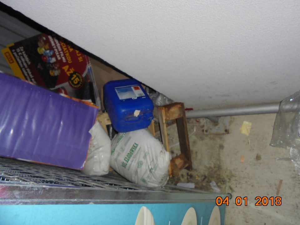 V rohu manipulačnej chodby pohádzané predmety nesúvisiace s činnosťou, plesnivá paleta, plastová nádoba, propagačné materiály, znečistená podlaha a zvyšky obalových materiálov.