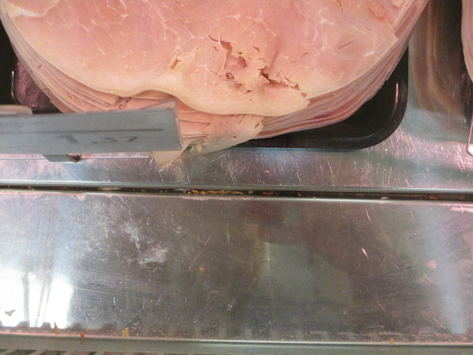 pult chladiarenského  pultu medzi a pod nerezovými platňami znečistený kúskami predávaných potravín 