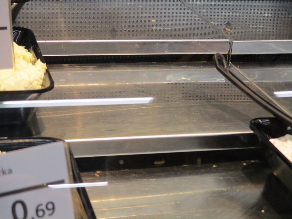 pult chladiarenského obslužného pultu medzi a pod nerezovými platňami znečistený kúskami predávaných potravín 