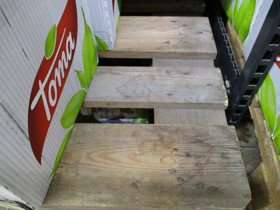 Znečistené podlahy pod regálmi a paletami na predajnej ploche.