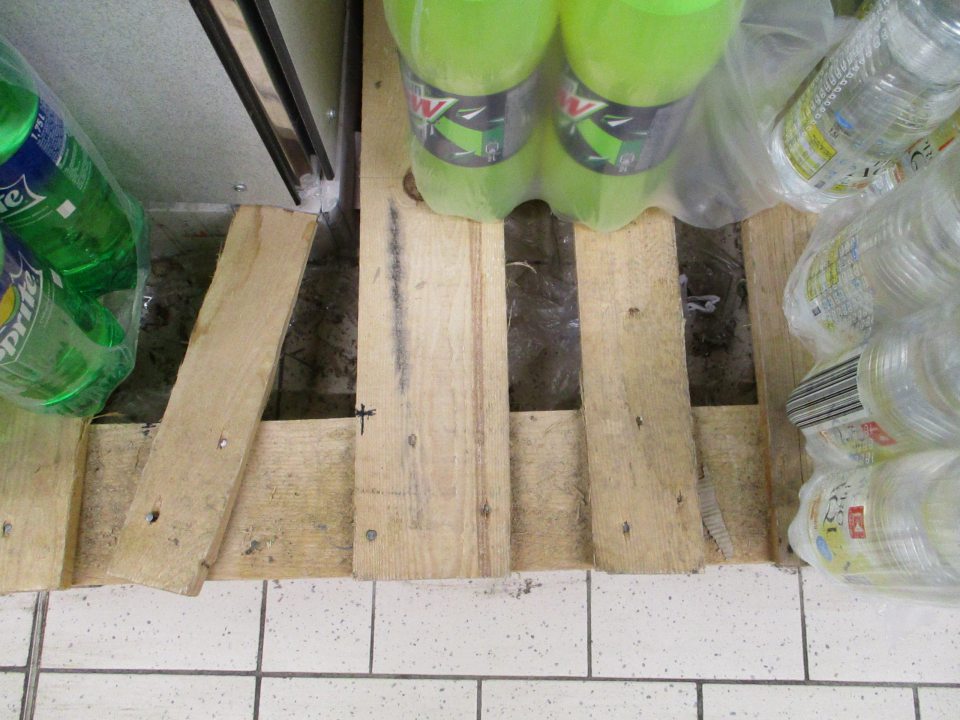 Znečistené podlahy pod regálmi a paletami na predajnej ploche.