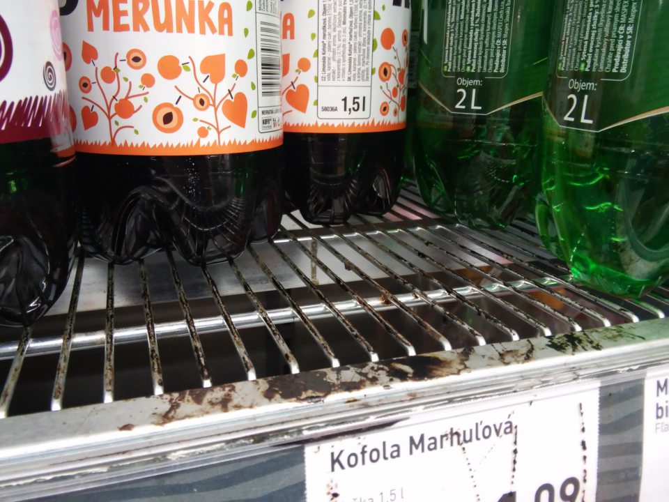 Znečistený regál s kofolou.