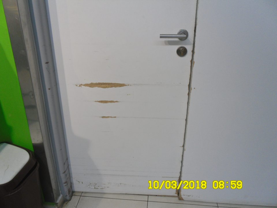 Dvere z predajnej plochy do skladu potravín v zlom stave údržby - poškodený povrch 