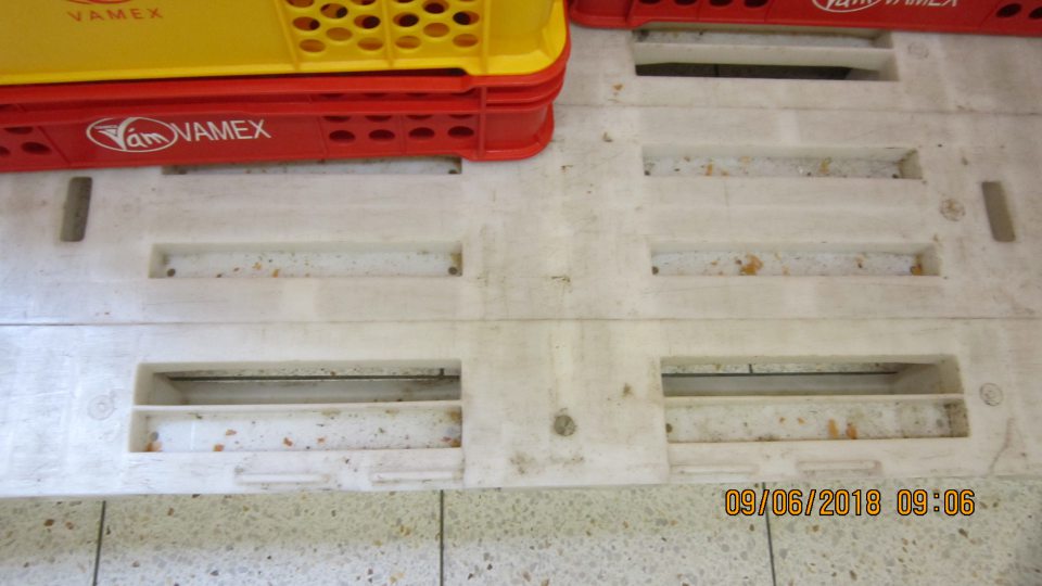 V priestore dopeku pekárskych výrobkov znečistené biele palety nánosom špiny, nečistôt a zvyškami pekárskych výobkov.  