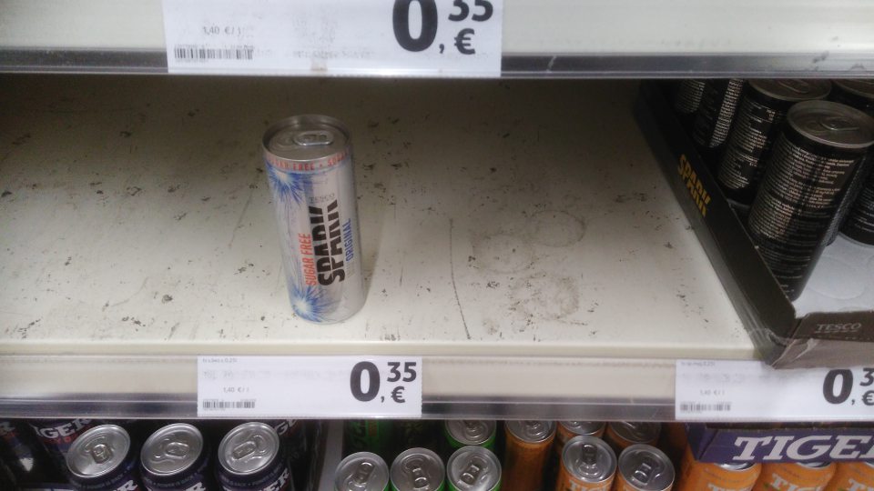Znečistená a poškodená ložná plocha regálu s energet. nápojmi v predajni