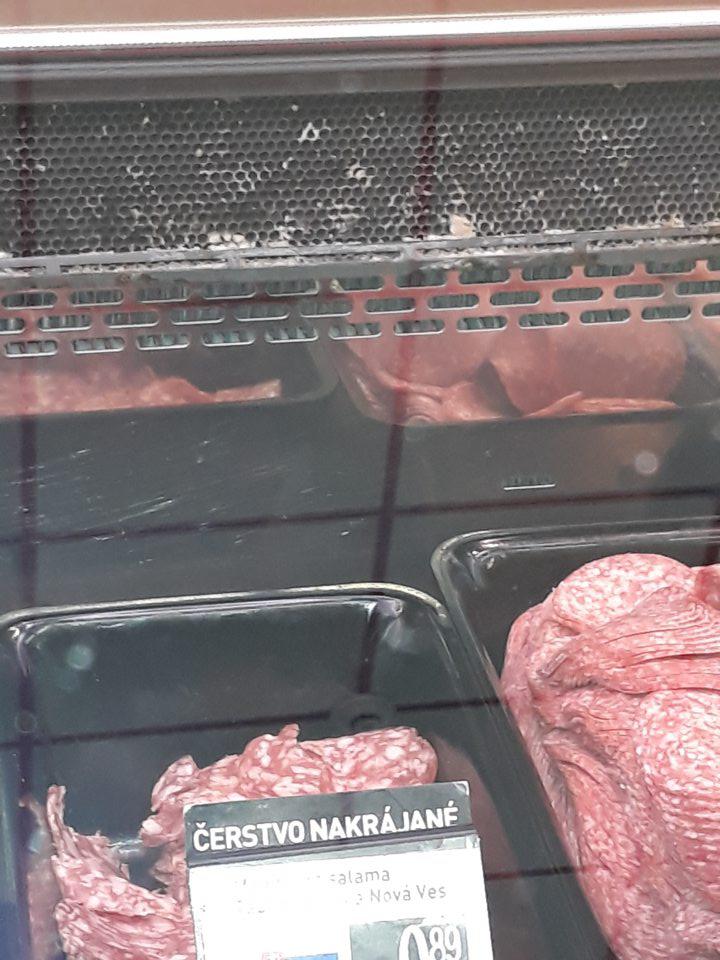 Znečistená mriežka zadnej steny chladiacej vitríny na mäsové výrobky pod pultom v predajni