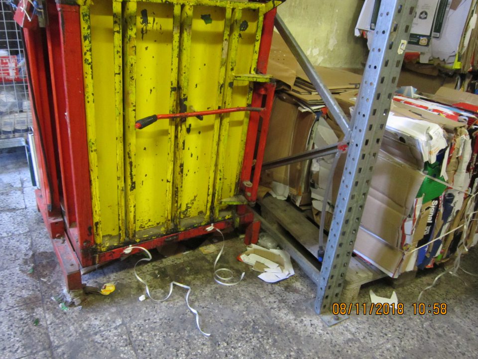 V okolí lisu na komunálny odpad znečistená, zaprášená podlaha. 