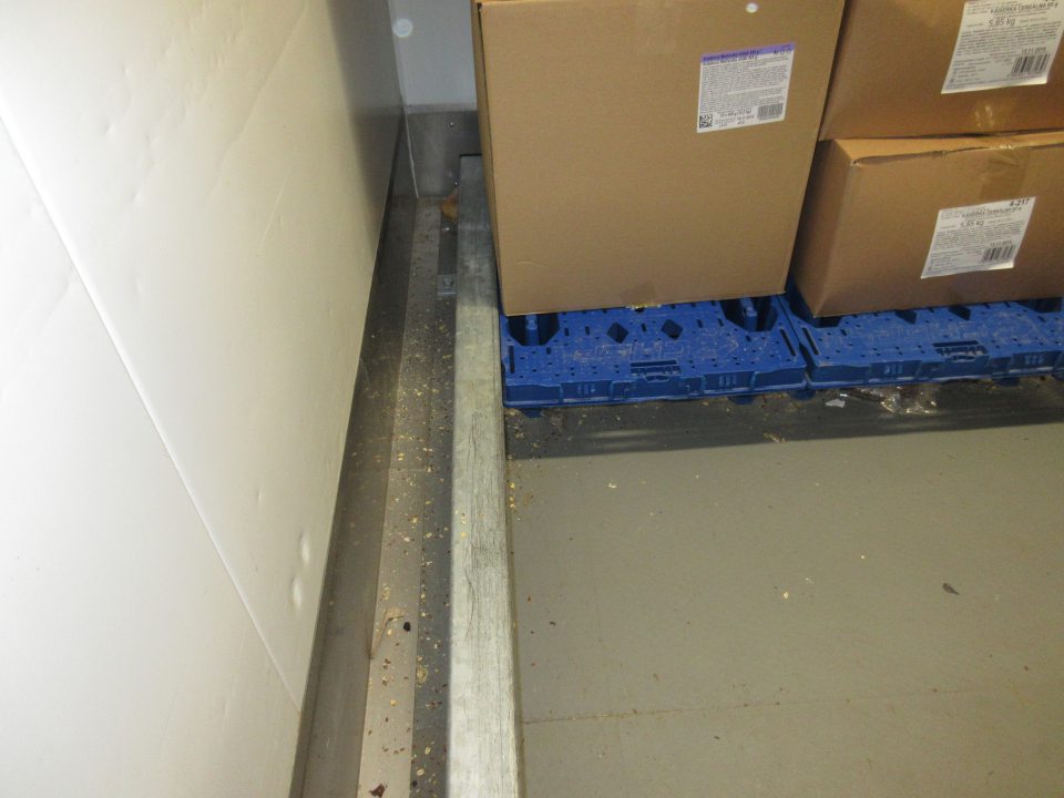 Znečistená podlaha mraziarenského skladu na skladovanie mrazeného pečiva určeného na dopek - omrvinky, obalový materiál.