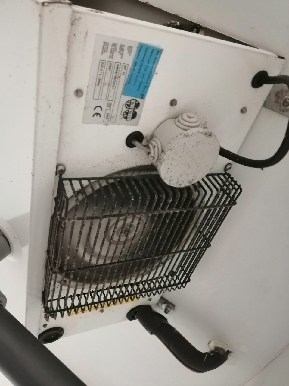 Znečistená mriežka ventilátora chladiacej jednotky a jej povrch v chladiacom boxe mliečnych výrobkov.