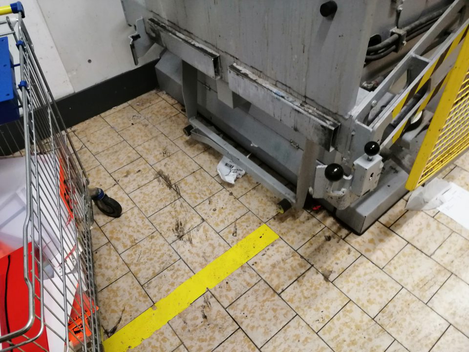 Znečistený lis na papier a podlaha v okolí.