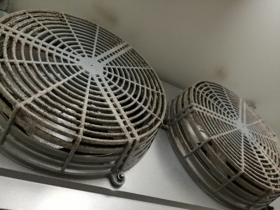 Znečistené mriežky ventilátorov chladiacej jednotky v chladenom sklade ovocia a zeleniny.