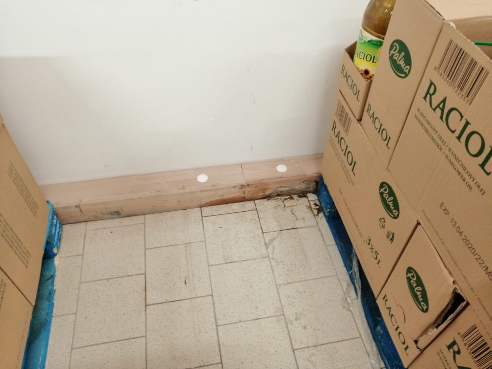 Znečistená podlaha pri paletových pozíciách a znečistené drevené zábrany v suchom sklade.