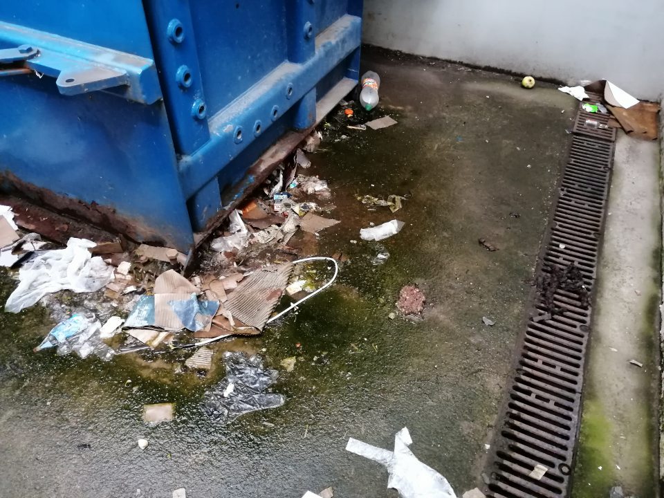 Znečistený povrch v okolí veľkokapacitného kontajnera vo vonkajšom priestore príjmu potravín.