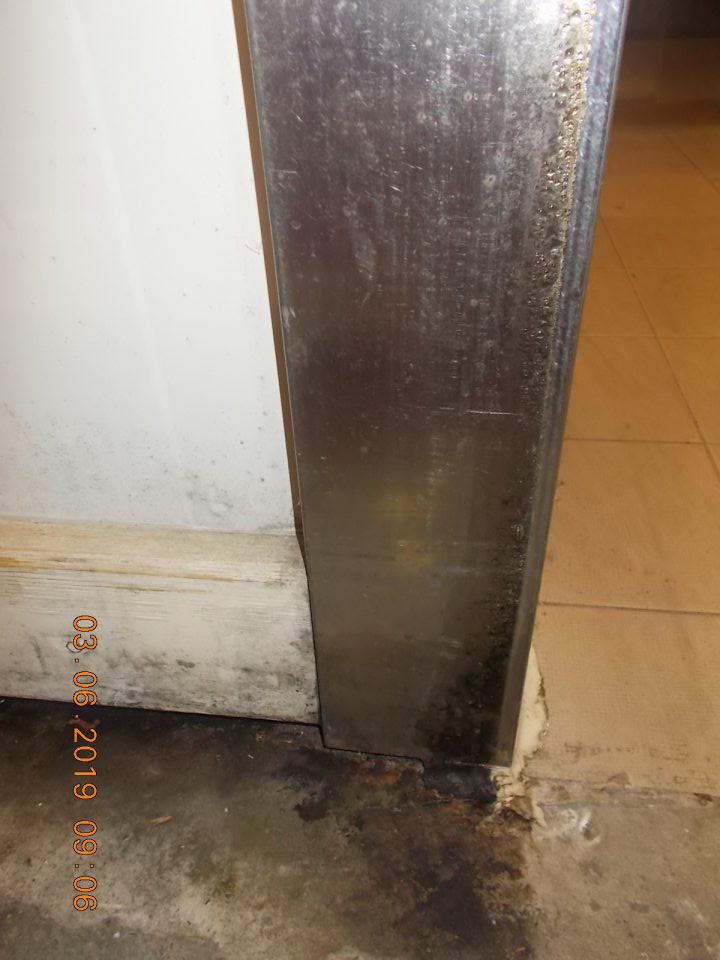 Znečistená podlaha a zárzbne dverí čiernou špinou pravdepodobne plesňou pri vstupe do chladiarenskeho boxu chladeného mäsa.