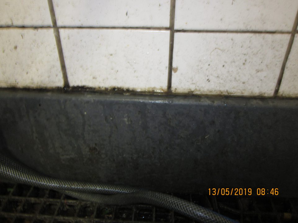 Nadmerne znečistené obkladačky od čiernej starej špiny, nánosy špiny v okolí výlevky