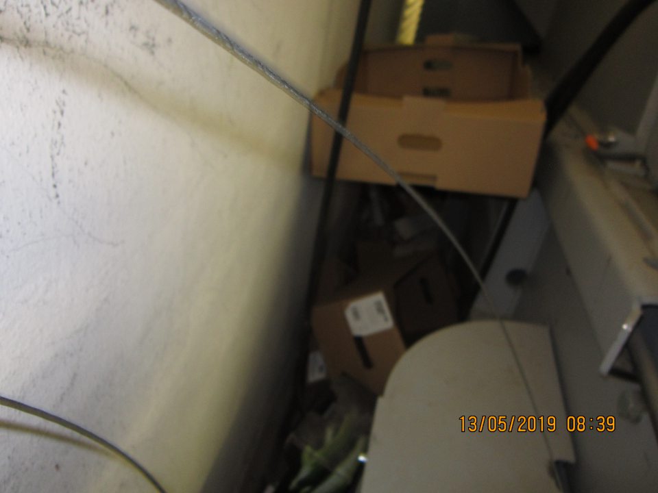 Veľký neporiadok za lisom na kartóny,prach, popadané kartóny, čierna špina, zbytky kartónov,kotúče drôtov