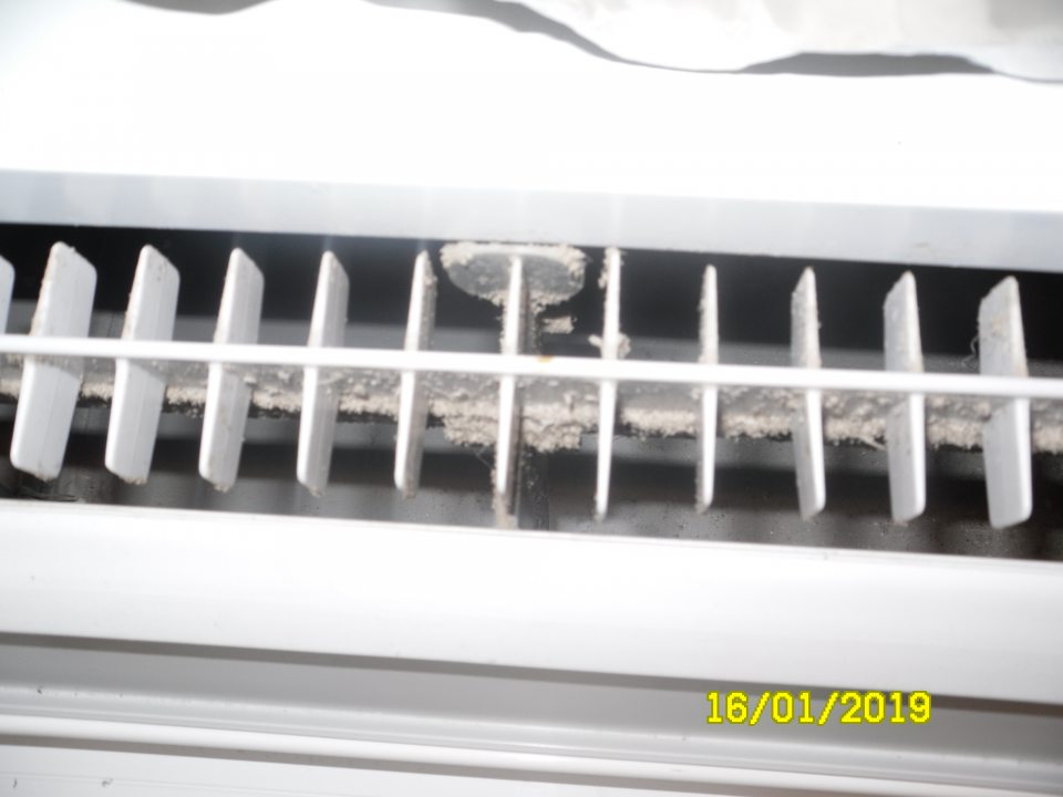 Silne znečistené mriežky v chladiarenskej vitríne s mliečnymi výrobkami na predajnej ploche.