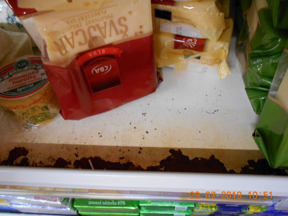 Skorodované regále chladiarenskej vitríny s uloženými mliečnymi výrobkami- syry.