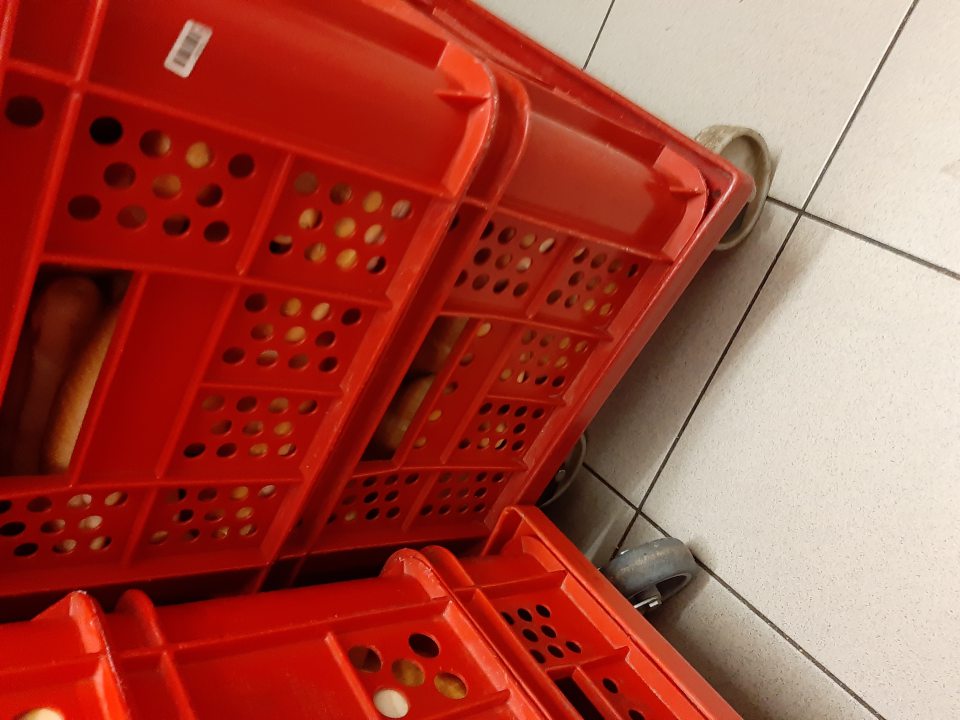 Nebalené pečivo skladované na manipulačnom vozíku bez podložnej prepravky.
