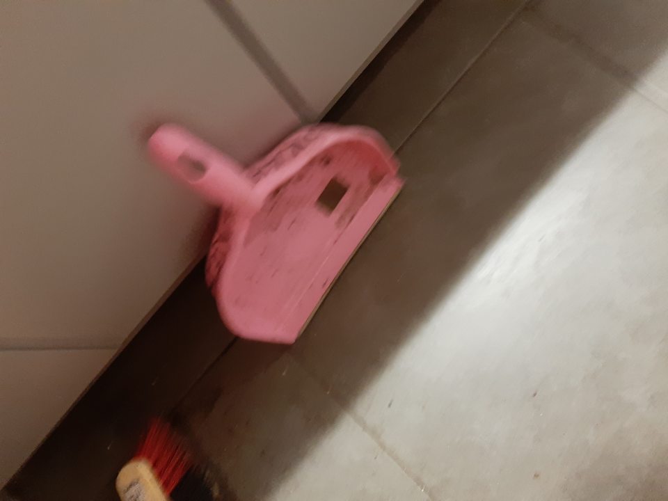 Plastová lopatka na vykonávanie upratovacích prác znečistená hrubýni nečistotami, nalepeným prachom.