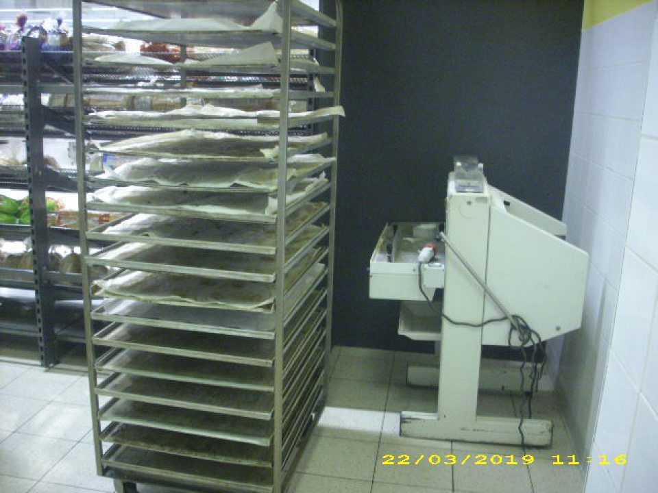 V priestoroch prípravy na pečenie v blízkosti stojana na plechy, na ktoré sa ukladajú pekárske výrobky, je umiestnená rezačka chleba, ktorá sa nepoužíva.