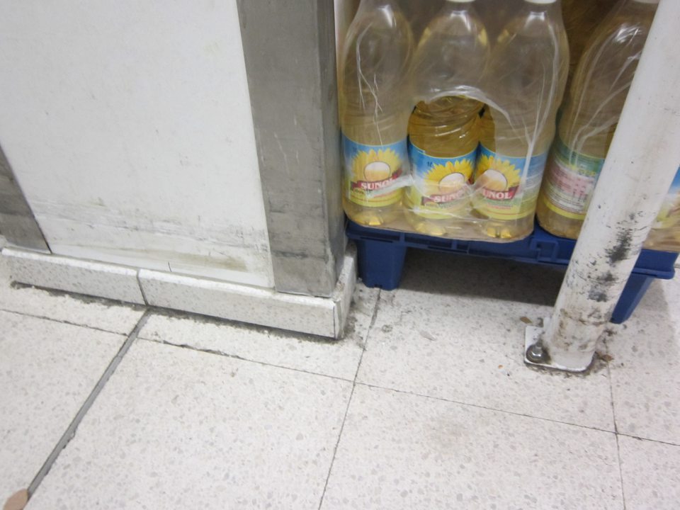 Pri stĺpe, pri ktorom je umiestnený regál s dopredávaným tovarom, podlaha znečistená nánosmi zaschnutej čiernej špiny.