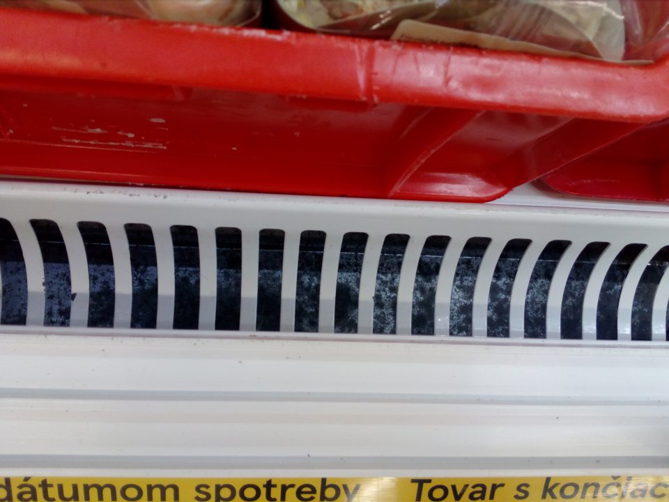Znečistenie chladiacej vitríny na predajnej ploche slúžiacej na uchovávanie mliečnych výrobkov, tovaru s končiacim dátumom spotreby na ťažko dostupných miestach pod mriežkami.
