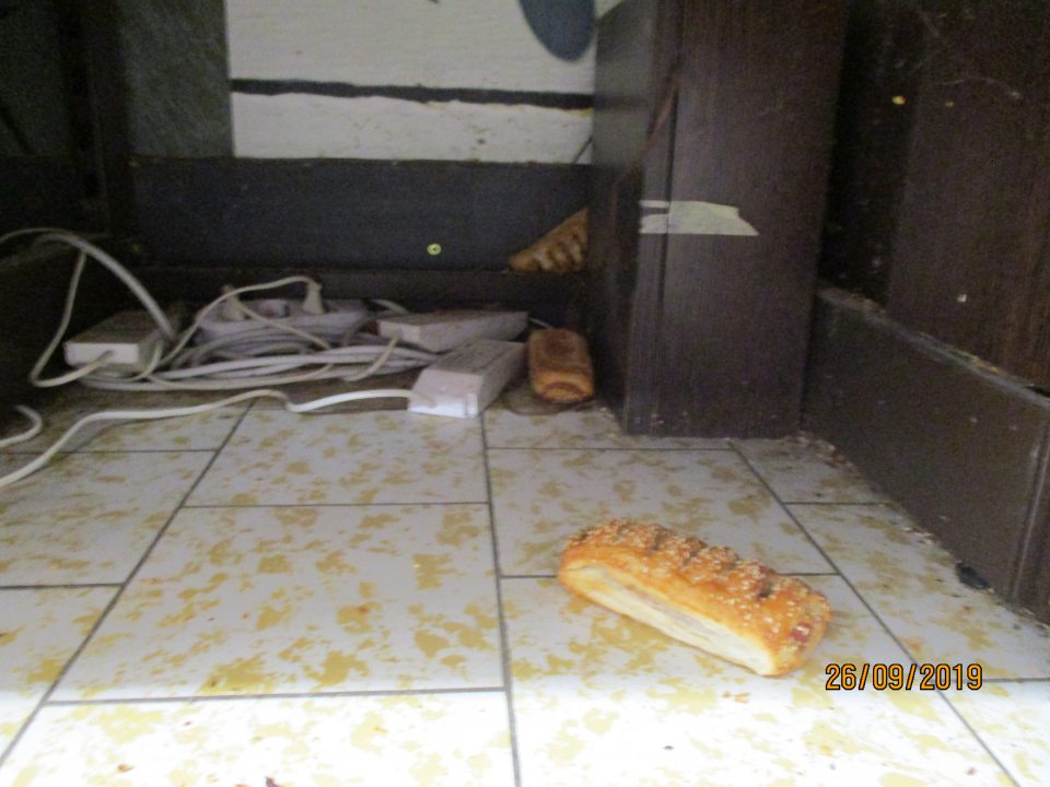 Znečistený priestor pod regálmi s nebalenými pekárskymi výrobkami.