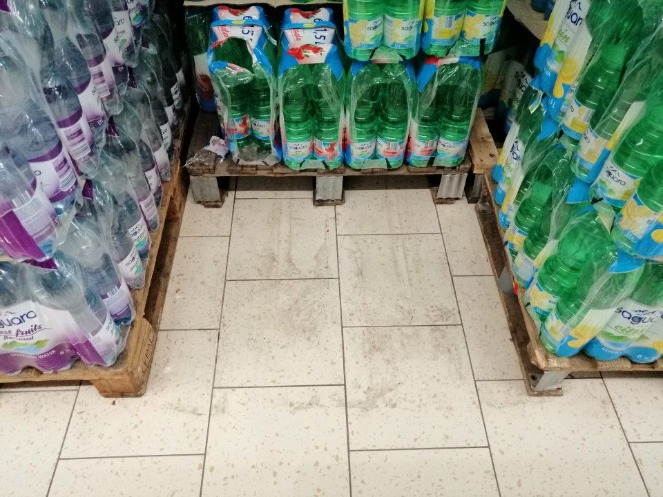 Znečistenie podlahy na predajnej ploche, hlavne v častiach medzi paletami s nealkoholickými a alkoholickými nápojmi.