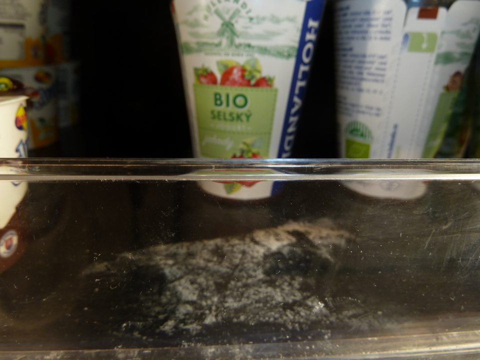 Znečistená polica v chladničke pre mliečne výrobky.