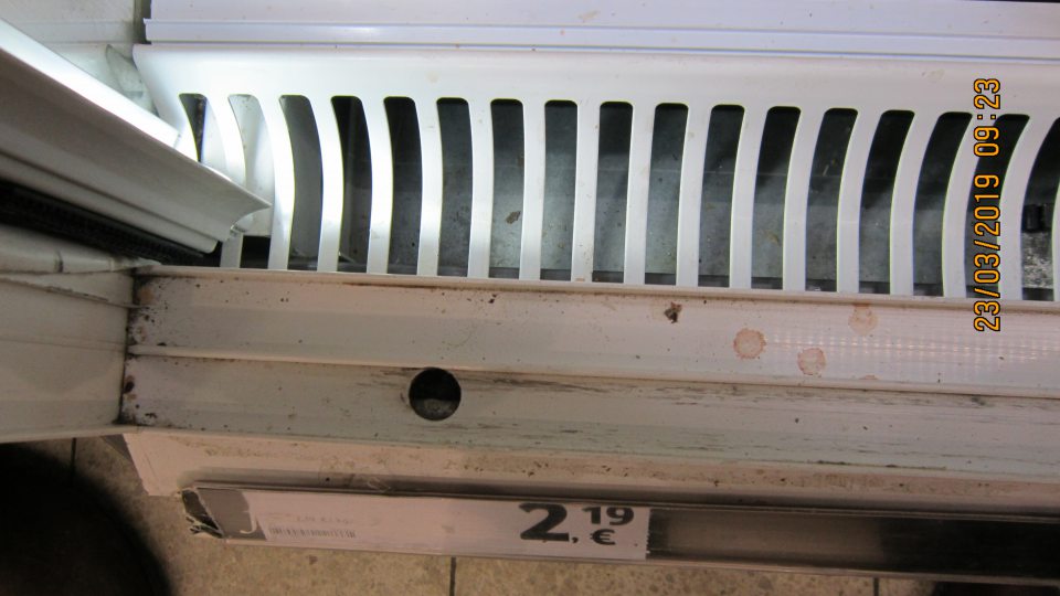 Na predajnej ploche v chladiacej vitríne znečistenie zasúvacej lišty posuvných dverí
od nečistôt a zaschnutej tekutiny červenej farby. 