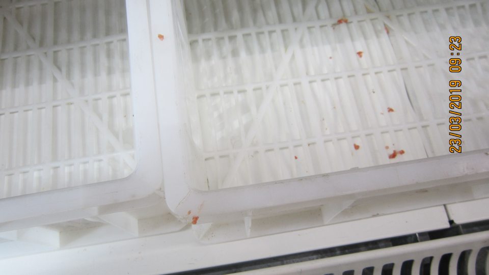 Na predajnej ploche na spodnej polici chladiacej vitríny znečistenie zaschnutou tekutinou a kúskami mletého mäsa.   