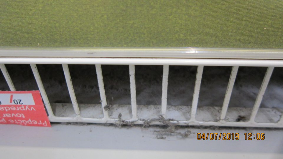 Znečistenie mriežky v spodnej časti chladiacej vitríny nánosom prachu a nečistôt.