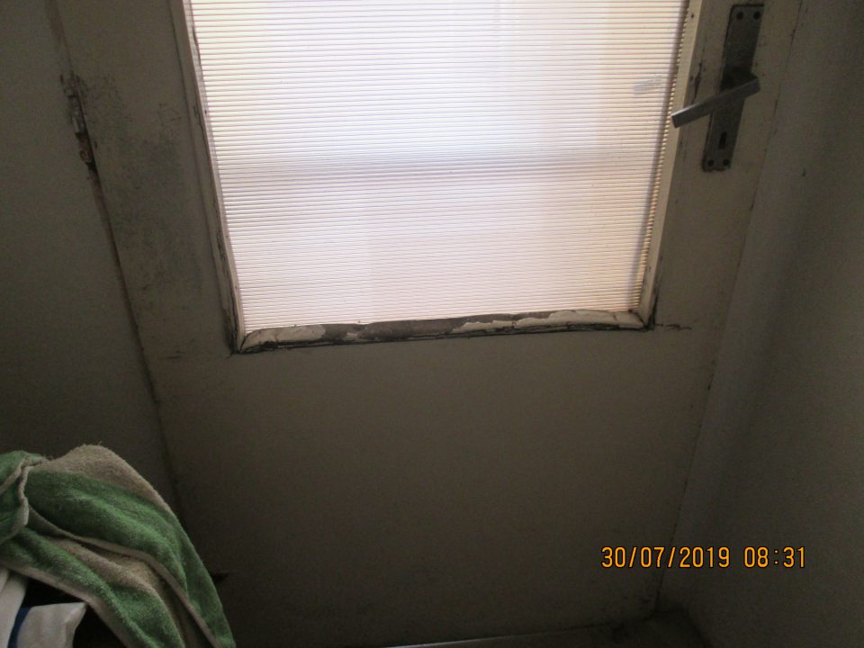 Poškodené vstupné dvere z vnútornej strany z vonkajšieho prostredia do prechodovej chodby.