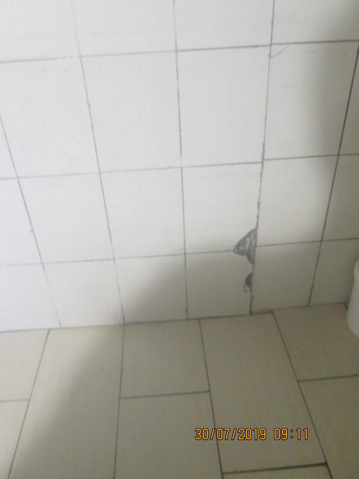 Poškodený keramický obklad vo vnútri kysiarne oproti vstupným dverám. 