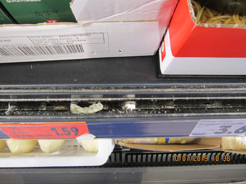 Prachom a zvyškami potravín znečistený priestor za cenovkovými lištami chladiacich vitrín. 