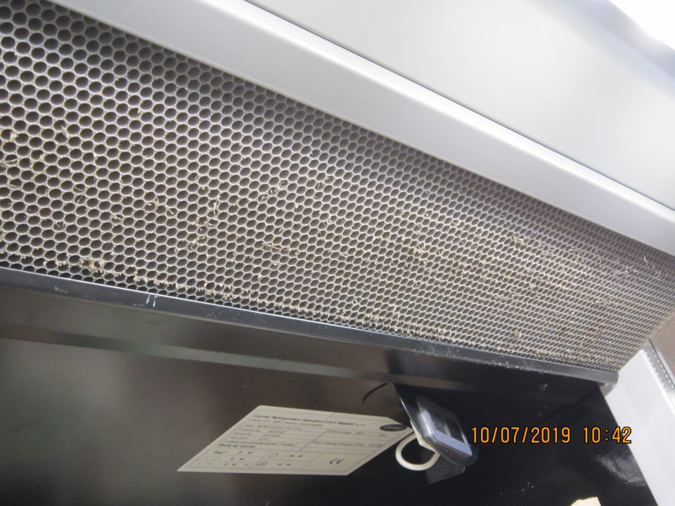 Hrubou vrstvou prachu znečistená mriežka vo vrchnej časti chladiacej vitríny balených vajec. 