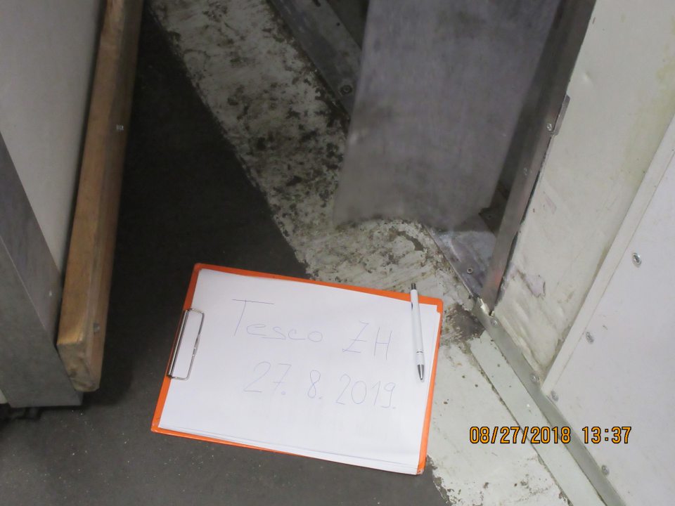 Poškodená a znečistená podlaha pri prechode z manipulačnej chodby do mraziarenského boxu.