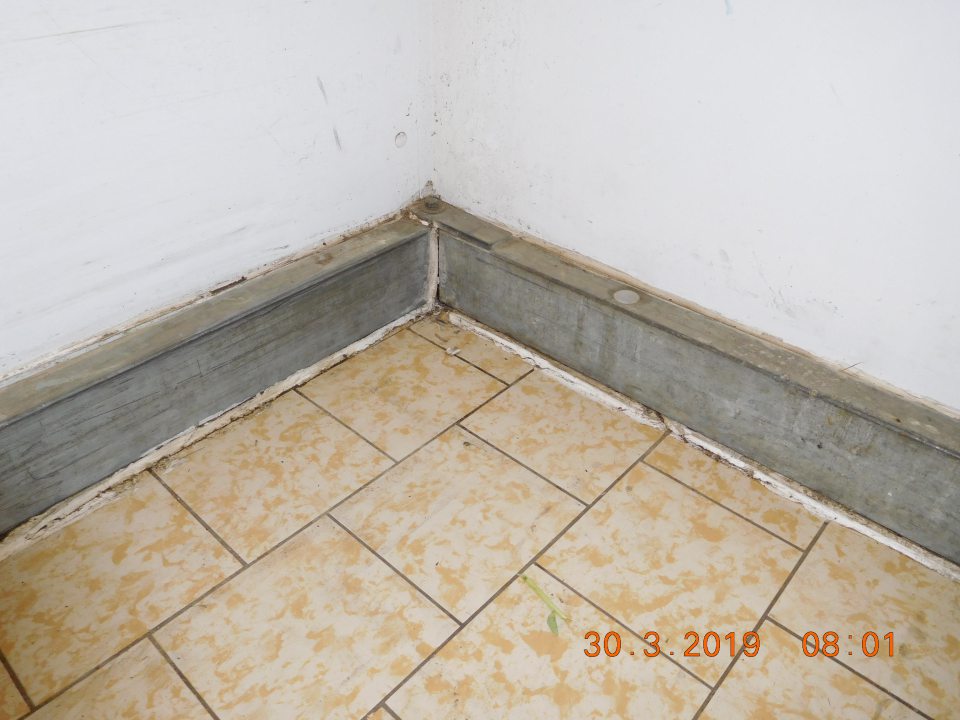 V  priestore skladu oproti vstupu do vonkajšieho prostredia mechanické poškodenie podlahovej lišty, porušenie až úplný rozpad tesniaceho tmelu okolo podlahovej lišty.