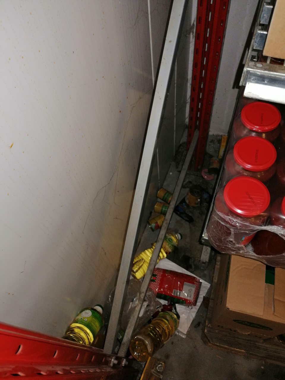 Popadaný tovar za regálmi v sklade.