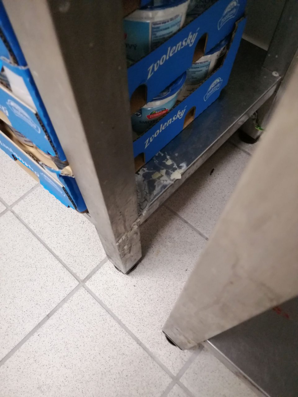 Znečistené police regálov v chladenom sklade mliečnych výrobkov.