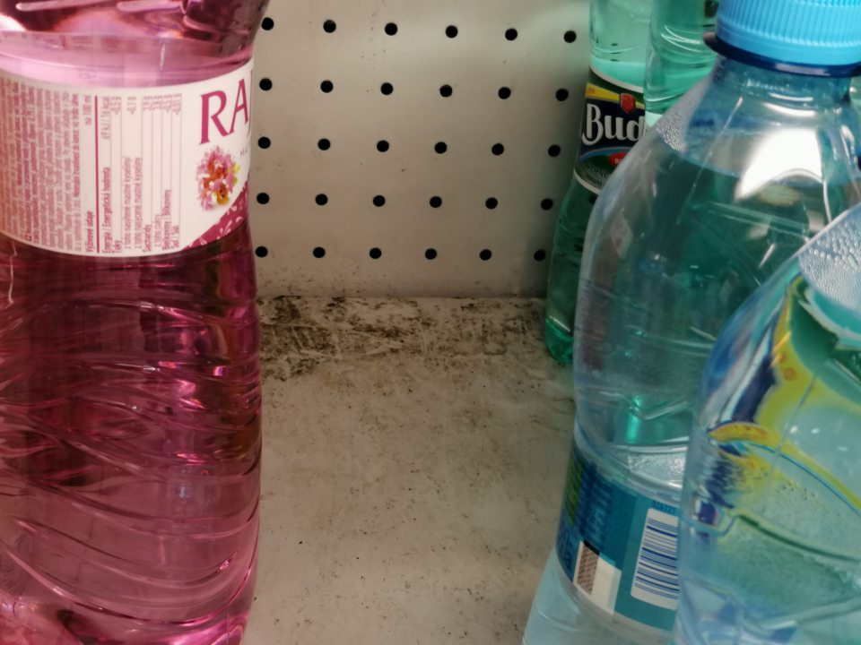 Znečistené police v chladiacej vitríne s nealko nápojmi.