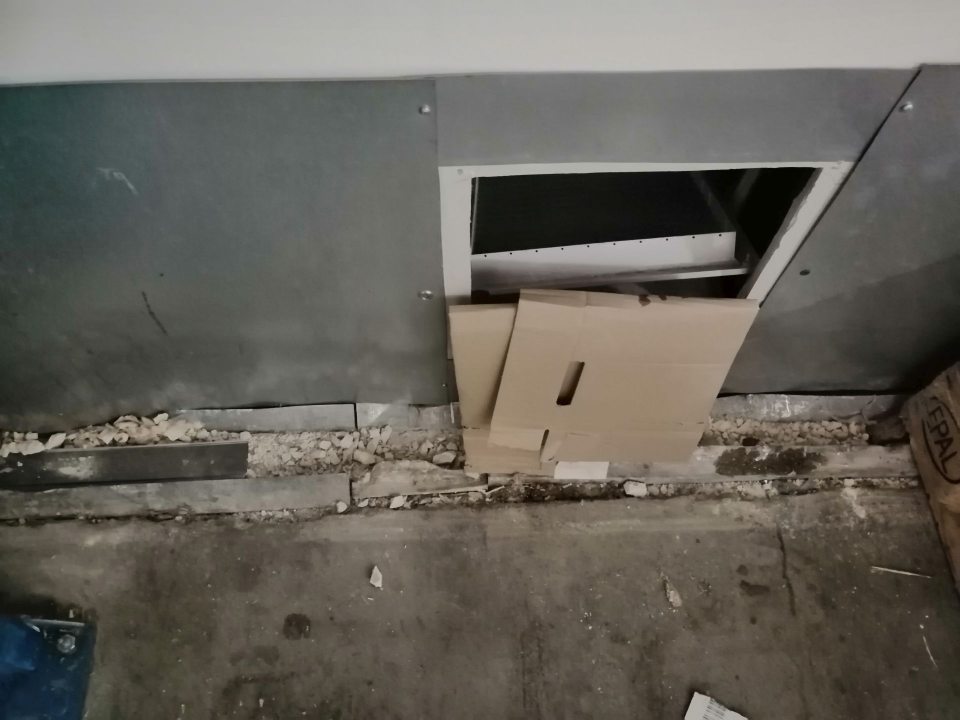 Poškodená stena a popadaná omietka v suchom sklade.