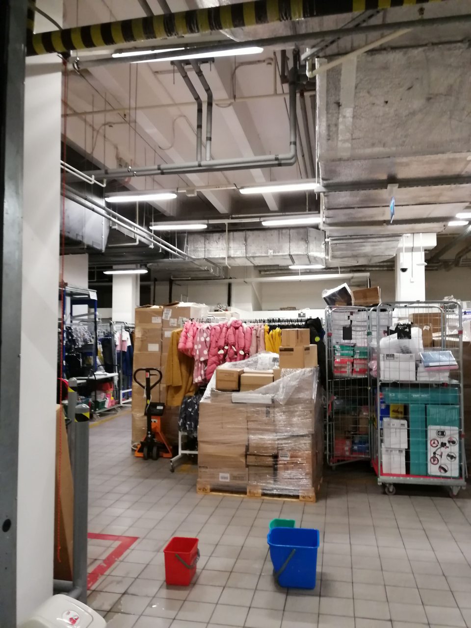 Kvapkajúca voda zo stropu do vedier v sklade tovaru.