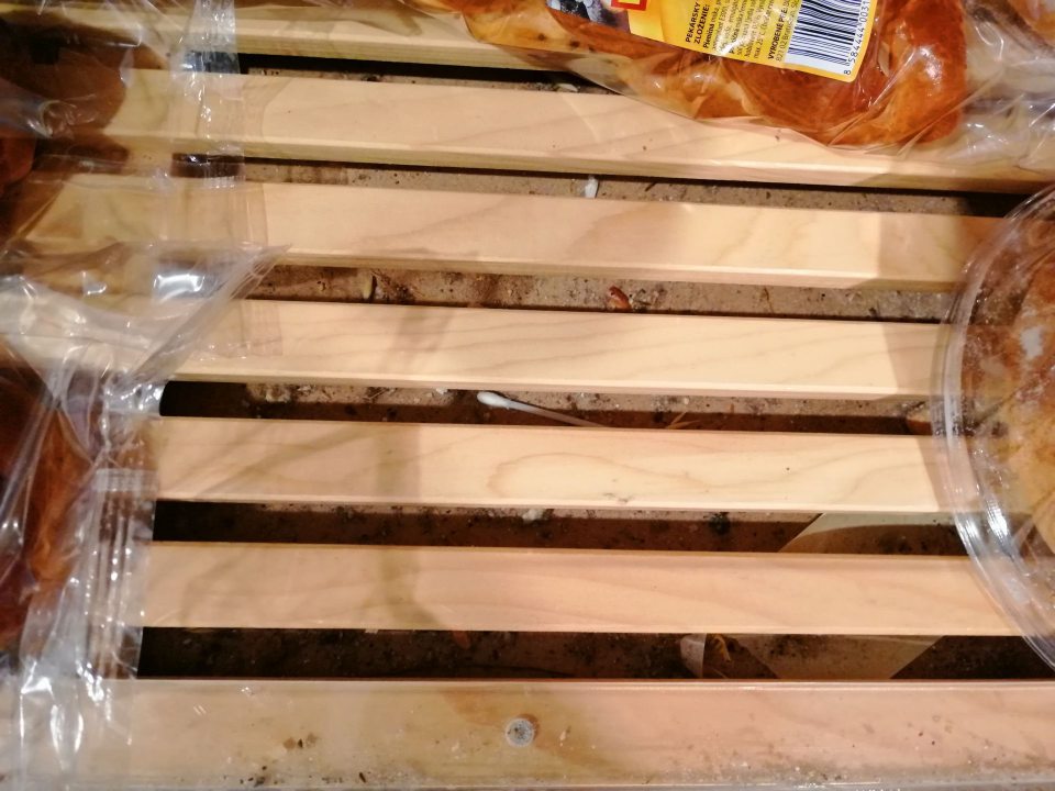 Nános nečistôt pod drevenými mriežkami spodnej police s pekárskymi výrobkami.