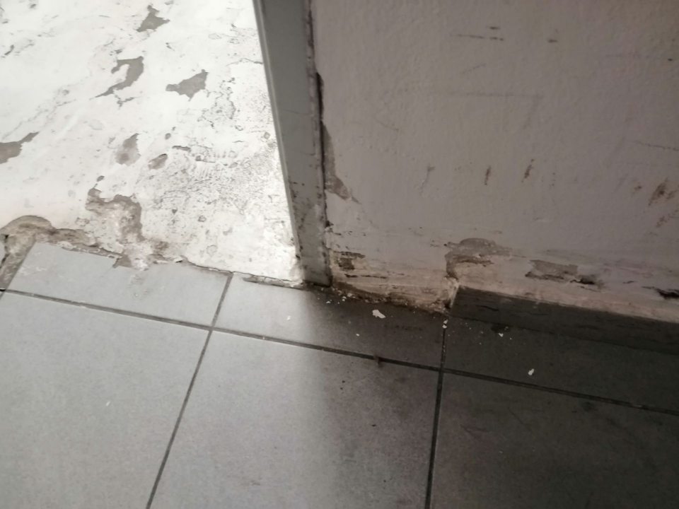 Poškodená dlažba, steny a chýbajúca časť soklov v manipulačnej chodbe.