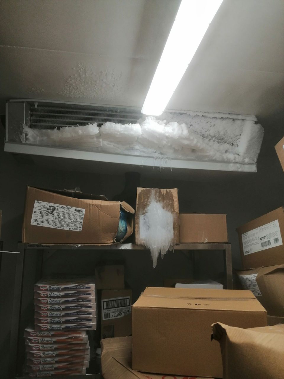 Vrstva ľadu na agregáte a krabiciach s tovarom.